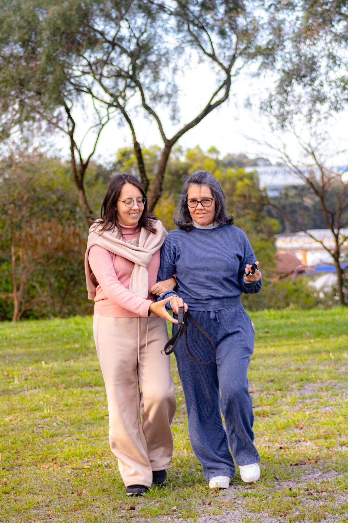 A caregiver walking closely arm-in-arm with a person she supports, outdoors